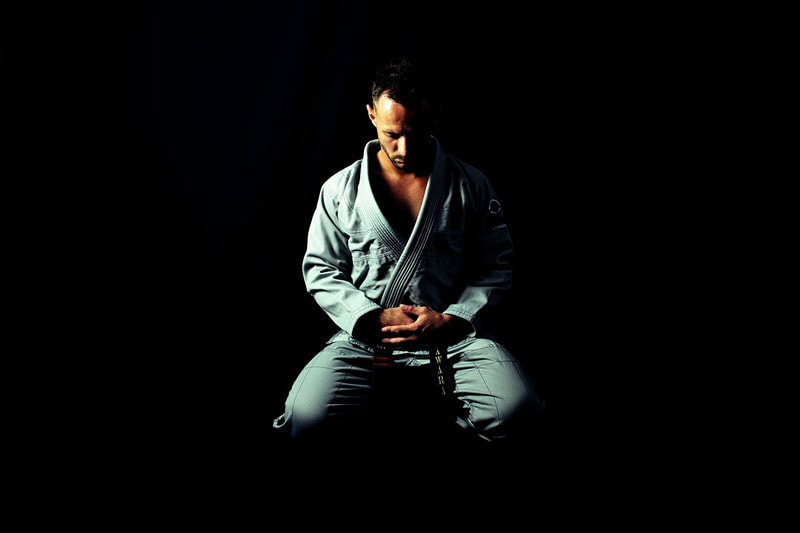 European man wearing a martial arts gi, sitting on the floor meditating: massage is for everyone and helps achieve health goals