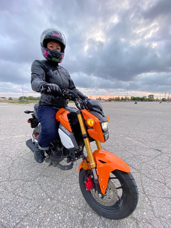 About Jun Ichino RMT: Jun posing on an orange Honda Gromm at her motorcycle course